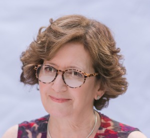 Mally Becker author photo, headshot of white female with short, brown curly hair, and tortoise shell eyeglasses