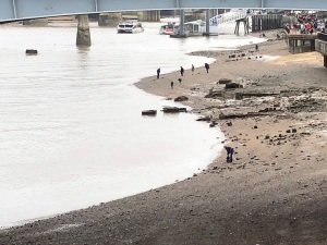 Photo of people "mudlarking" on the shore of the Thames