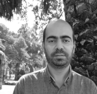 Mohammed Said Hjiouij photo: black and white photograph of a Moroccan/North African gentleman with mustache and short beard, wearing a button-down shirt and standing in front of a palm tree